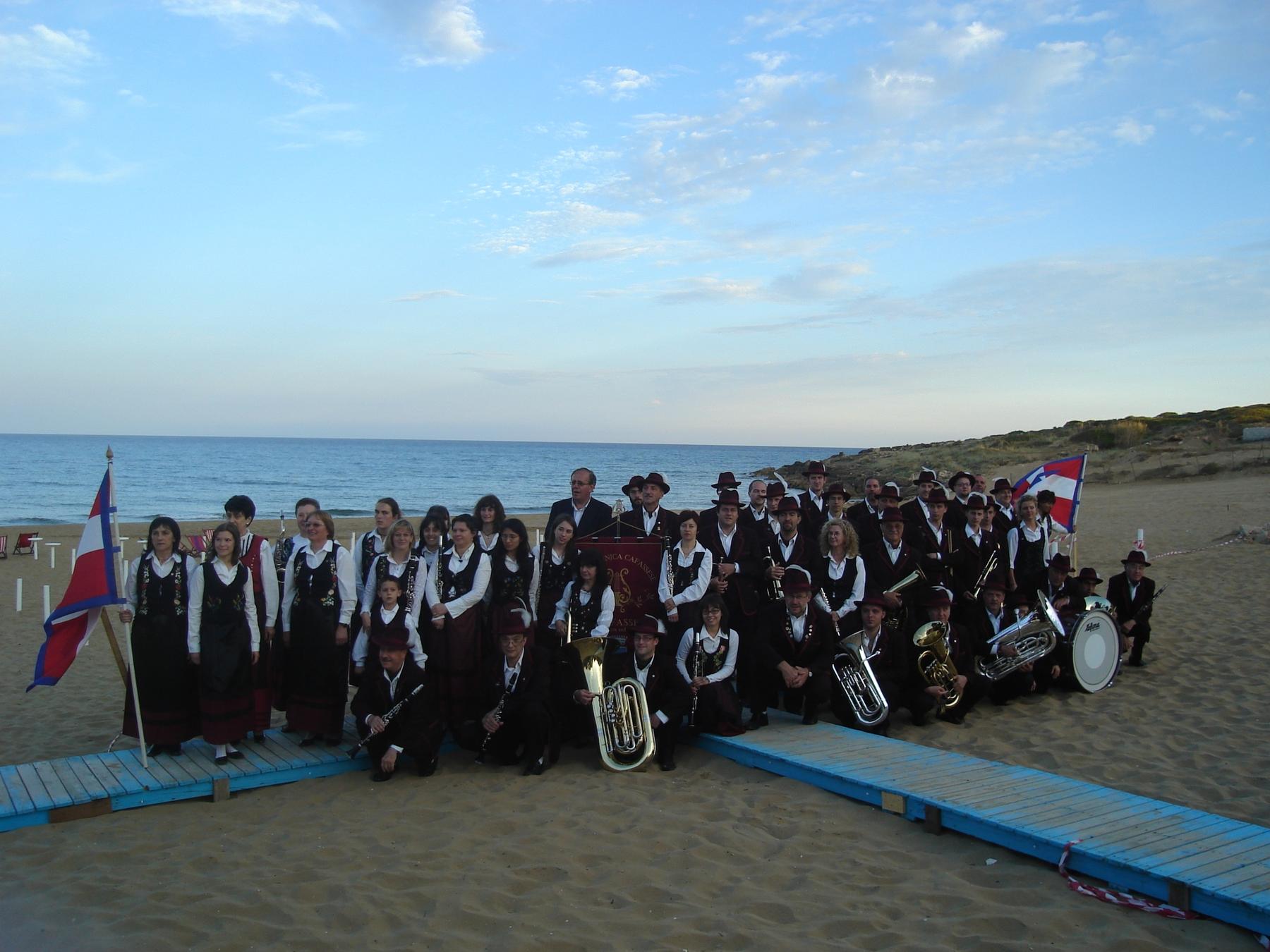La Filarmonica Cafassese in costume sulla spiaggia di Noto al tramonto, con la bandiera del Piemonte